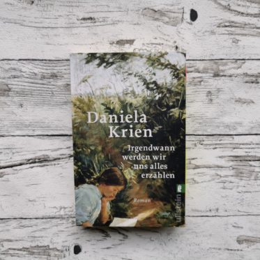 Das Buch "Irgendwann werden wir uns alles erzählen" von Daniela Krien auf einem hellen, holzähnlichen Hintergrund. Das Bild ist das Headerbild des Blogbeitrags.