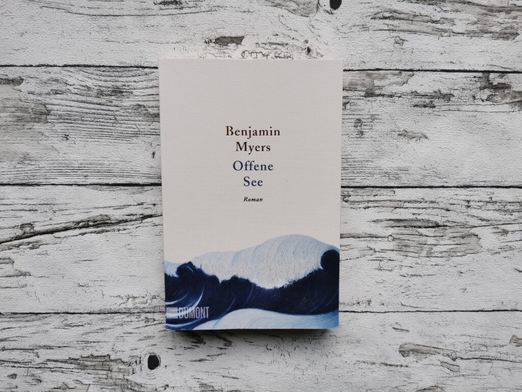Auf dem Bild ist das Buch "Offene See" von Benjamin Meyers auf einem hellen, holzähnlichen Hintergrund abgebildet. Es dient als Header-Bild für den Blogbeitrag.
