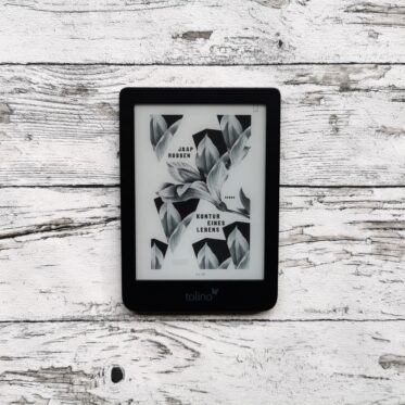 Auf dem Foto ist ein eBook Reader auf einer hellen, holzähnlichen Fläche abgebildet. Das Cover des Buchs "Kontur eines Lebens" von Jaap Robben ist zu erkennen.