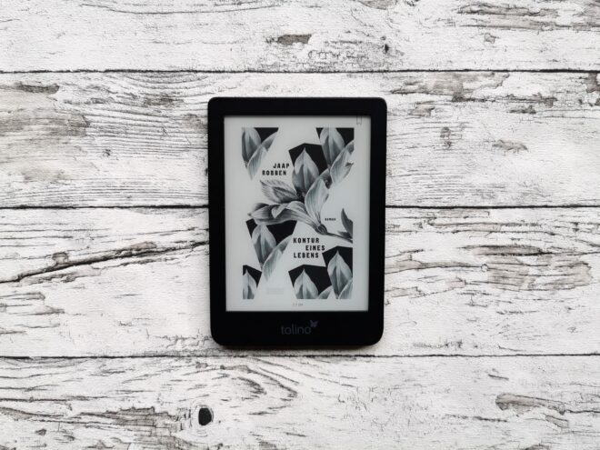 Auf dem Foto ist ein eBook Reader auf einer hellen, holzähnlichen Fläche abgebildet. Das Cover des Buchs "Kontur eines Lebens" von Jaap Robben ist zu erkennen.