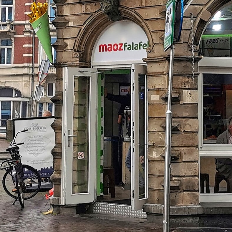 Auf dem Bild ist der Eingang einer Maoz Falafel Niederlassung in Amsterdam abgebildet.