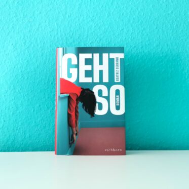 Auf dem Bild ist das Buch Geht so von Beatriz Serrano vor einer türkisen Wand auf einer hellen, glatten Oberfläche abgebildet. Es ist das Header-Bild der Rezension des Buches.