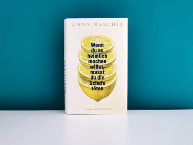 Auf dem Foto ist das Buch Wenn du es heimlich machen willst, musst du die Schafe töten von Anna Maschik auf einer weißen Oberfläche vor einer grünen Wand stehend abgebildet. Es ist das Header-Bild zur Rezension des Buches.