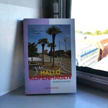 Auf dem Foto ist das Buch Hallo Kopenhagen auf einer Fensterbank im Rundetårn zu sehen. Es ist das Header-Bild zu einer Rezension des Buchs.